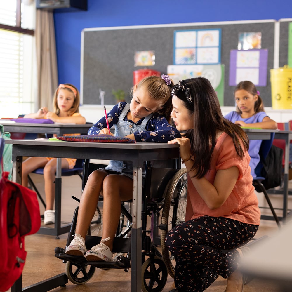 teacher-helping-student-at-desk